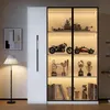 A well-lit display cabinet filled with various models and trophies, placed in a modern living room setting next to a floor lamp and artwork. Produktbild-Vorschau