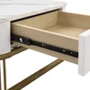 A close-up view of an open drawer on a white table with a marble-look top and gold legs. Voir les images du produit