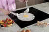 A person is pouring pancake batter into a special pan on an induction hob. A plate of finished pancakes with fruit is on the side. Náhľad obrázku produktu