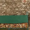 A firewood rack with a green cover in front of a stone wall. Náhled obrázku produktu