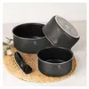 A set of black pots and a handle on a woven mat. Anteprima dell’immagine prodotto