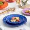 A table setting with colorful ceramic plates, food, and drinks. Produktbild-Vorschau