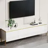 A white TV cabinet with gold accents and metal legs, with a TV mounted on the wall above it. Decorative items are placed on the cabinet. Anteprima dell’immagine prodotto