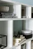A close-up view of a white modular shelving unit filled with various decorative items and books. Náhled obrázku produktu