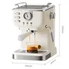A cream-colored espresso machine with chrome accents is shown from the front, with a small glass beaker collecting espresso. Produktbild-Vorschau
