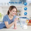 A woman is drinking water from a glass next to a water filter pitcher. Produktbild-Vorschau
