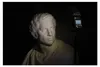 A white bust of a man is lit by a spotlight, with a camera flash unit on a stand to the right. Podgląd zdjęcia produktu