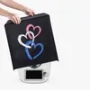 A hands are putting a decorative cover with hearts on a white kitchen appliance. Produktbild-Vorschau