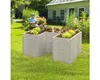 A person sits in a garden behind a raised garden bed filled with plants. Voir les images du produit