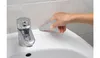 A hand is using a tool to apply sealant to the edge of a sink. Podgląd zdjęcia produktu