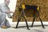 A man is cutting a piece of wood on a sawhorse. Anteprima dell’immagine prodotto