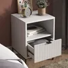 A white nightstand with an open drawer, displaying books and a plant on top. Voir les images du produit