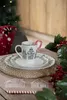 A festive Christmas table setting with a mug, plates, and decorations. Anteprima dell’immagine prodotto
