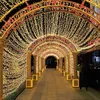 A person walks through a tunnel decorated with numerous warm white and red fairy lights, creating a festive and magical atmosphere. Náhľad obrázku produktu