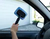 A hand holding a car window cleaning tool inside a car, with a garage door visible through the window. Produktbild-Vorschau