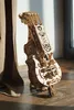 A wooden 3D puzzle of a hurdy-gurdy is displayed on a wooden surface, next to a draped fabric. Produktbild-Vorschau