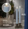Two blue LED candles in glass candle holders on a windowsill with a small Christmas tree and fairy lights in the background. Produktbild-Vorschau