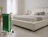 A green oil-filled radiator is placed on the floor next to a bed in a bedroom. Náhled obrázku produktu