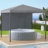An inflatable hot tub is set up on a wooden deck under a gray canopy structure. The scene is outdoors with a view of the ocean and greenery in the background. Náhled obrázku produktu