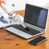 Weißer und oranger Handstaubsauger mit Bürstenaufsatz reinigt eine Laptop-Tastatur Produktbild-Vorschau