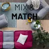 An overhead view of modular sofa pieces, beanbag chairs, rugs, and decorative items arranged on a textured outdoor surface. Produktbild-Vorschau