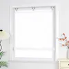 A white patterned roller blind is installed in a window frame, with a lamp and a plant visible to the left, and a vase with branches to the right. Produktbild-Vorschau
