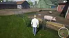 A person walks on a farm near a pig pen with pigs and farm buildings in the background. Anteprima dell’immagine prodotto