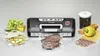 A vacuum sealer machine with various food items and accessories arranged around it. Produktbild-Vorschau