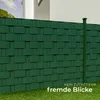 A green fence made of privacy strips is shown in front of a white building and green grass. Náhled obrázku produktu