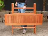A person is holding a wooden garden table that appears to be foldable. Produktbild-Vorschau