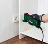 A person wearing a glove is using a green multi-tool to work on a white shelf. Produktbild-Vorschau