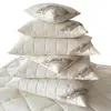 A stack of cream-colored pillows and a comforter, all with a quilted pattern and a label that reads 'Kuschelzeit'. Produktbild-Vorschau