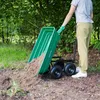 A person is using a green garden cart to dump soil in an outdoor setting with trees and grass. Podgląd zdjęcia produktu
