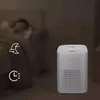An air purifier is shown in a bedroom setting with a person sleeping in the background. Icons representing sleep mode and a timer are visible. Produktbild-Vorschau