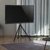 A black TV on a black tripod stand is shown in a room with a rug and curtains. Podgląd zdjęcia produktu