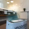 A white air purifier is placed in a modern bathroom with a marble countertop and sink. Produktbild-Vorschau