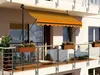 A balcony with a striped awning and flower boxes. Produktbild-Vorschau