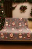 A Christmas-themed blanket with Santa and snowman patterns is draped over a sofa in a room decorated for Christmas. Náhled obrázku produktu