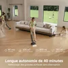 Two women are cleaning a modern living room with a large sofa and large windows overlooking a green lawn. One woman is using a wet/dry vacuum cleaner, and the other is kneeling and appears to be cleaning a baseboard. Produktbild-Vorschau
