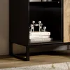 Close-up view of the lower section of a black cabinet with a wooden door, showing books and decorative items on a shelf. Produktbild-Vorschau