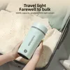 A person is holding a light green portable kettle in a suitcase filled with clothes. Produktbild-Vorschau