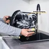 A person is cleaning the removable basket of an air fryer in a kitchen sink. Produktbild-Vorschau