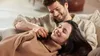 A couple relaxing on a couch, with the woman resting her head on the man's lap. Produktbild-Vorschau