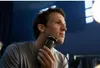 A man is shaving his face with an electric razor in front of a mirror. Produktbild-Vorschau