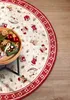 A round Christmas-themed rug with various festive motifs is partially visible, with a wooden table holding Christmas decorations in the foreground. Podgląd zdjęcia produktu