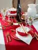 A beautifully set table with red runner, plates, glasses, cutlery, a bottle of wine, and breadsticks. Produktbild-Vorschau