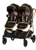A studio shot of a black and gold twin stroller against a white background. Produktbild-Vorschau