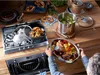 A person is cooking a meal in a kitchen setting with various cookware and food items. Podgląd zdjęcia produktu