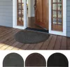 A half-moon shaped doormat placed on a wooden porch in front of an open wooden door. Produktbild-Vorschau