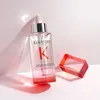 A bottle of Kérastase Genesis serum is displayed on a pink and white surface, with a red geometric object to the right. Produktbild-Vorschau